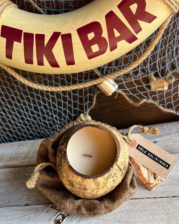 Tropical coconut candle in reclaimed shell surrounded by tiki décor, beach-inspired home decoration, vegan candle