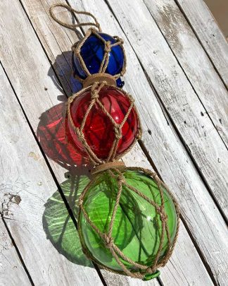 Triple glass fish float hanging décor in green, red, and blue, nestled in manila rope netting, inspired by vintage Japanese fishing floats for tiki and coastal home decor.