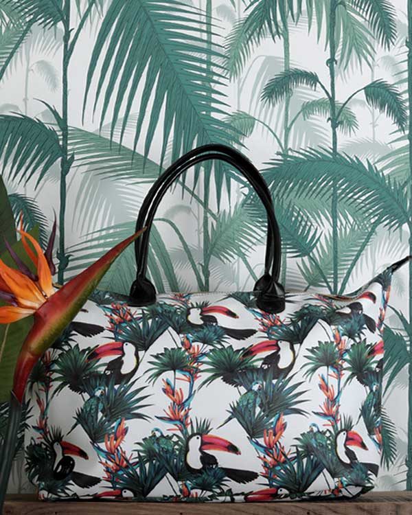 Tropical Print Holdall against a palm print wall paper with a bird of paradise flower