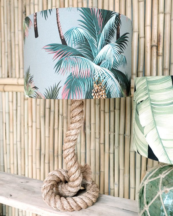 Tropical printed lampshade drum with rope base against bamboo wall
