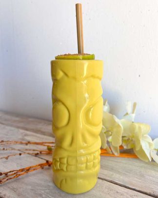 This is an image of a Plastic Tiki mug in the style of a zombie, it is bright lime green and styled with a bamboo straw and lime just like a dark and story cocktail.
