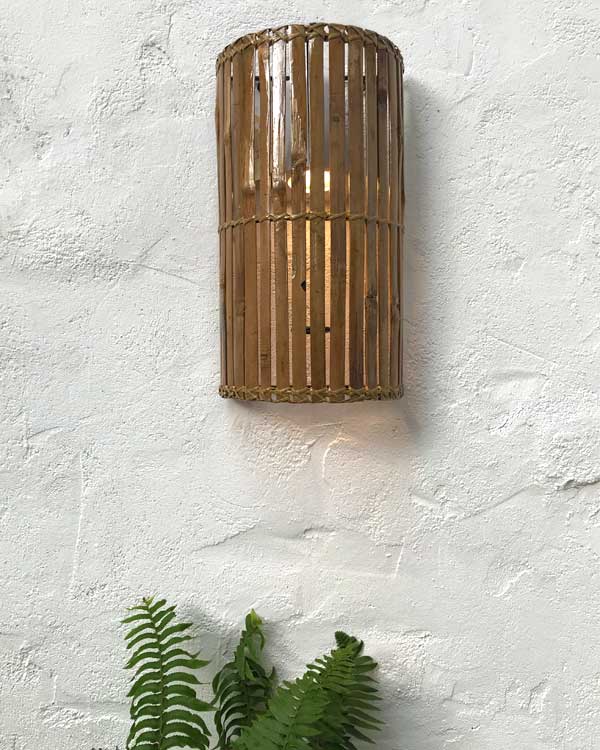 Bamboo wall light hung on a wall with light and plants