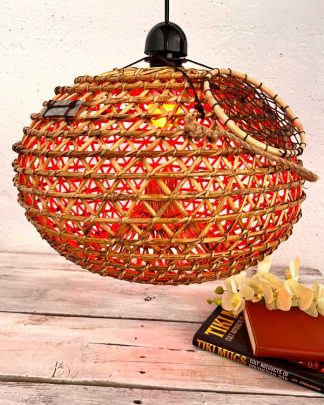 This is an image of a Decorative Fish Trap Pendant Light. It has a remote control Colour chnaging bulb shown in red and is set on a back drop of White Wsahed Drift wood and with Tiki Mugs Book and Orchid Stem in Cream.