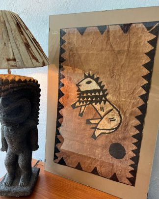 FRAMED VINTAGE SAMOAN TAPA CLOTH PIECE NEXT TO A TIKI LAMP