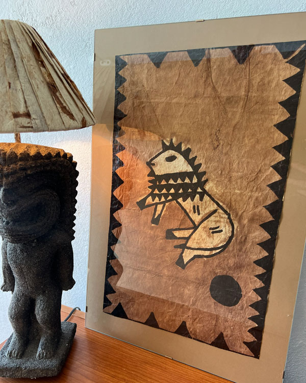FRAMED VINTAGE SAMOAN TAPA CLOTH PIECE NEXT TO A TIKI LAMP